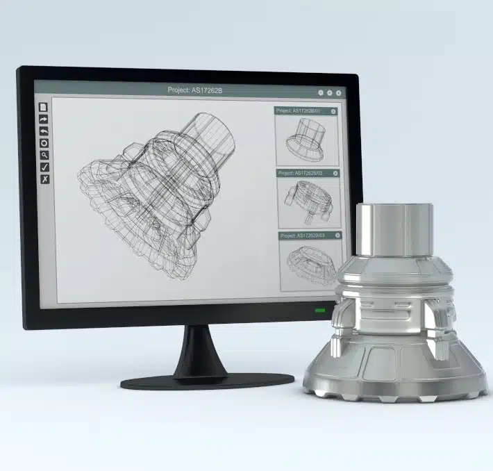 A computer monitor displays a technical wireframe drawing of a mechanical part, with the finished metal part placed beside the monitor.
