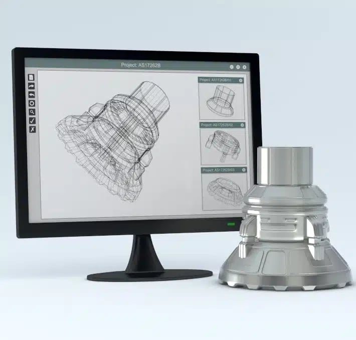 A computer monitor displays a technical wireframe drawing of a mechanical part, with the finished metal part placed beside the monitor.